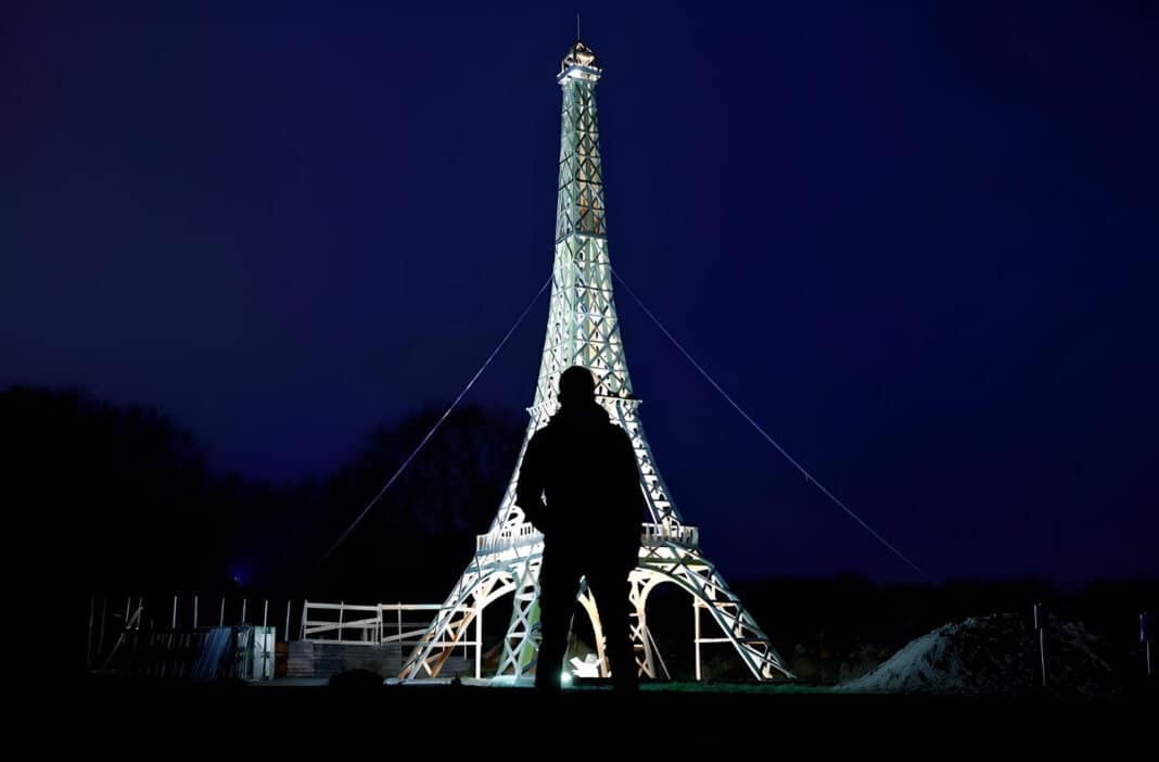 A man is silhouetted in front of a 16-meter replica of the Eiffel Tower built from recycled wood by French carpenter Frederic Malmezac. (Photo Credit: Reuters/Stephane Mahe)